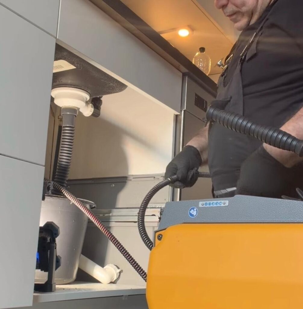 Mechanische Reinigung eines Abflussrohrs unter dem Waschbecken zur Beseitigung von Verstopfungen